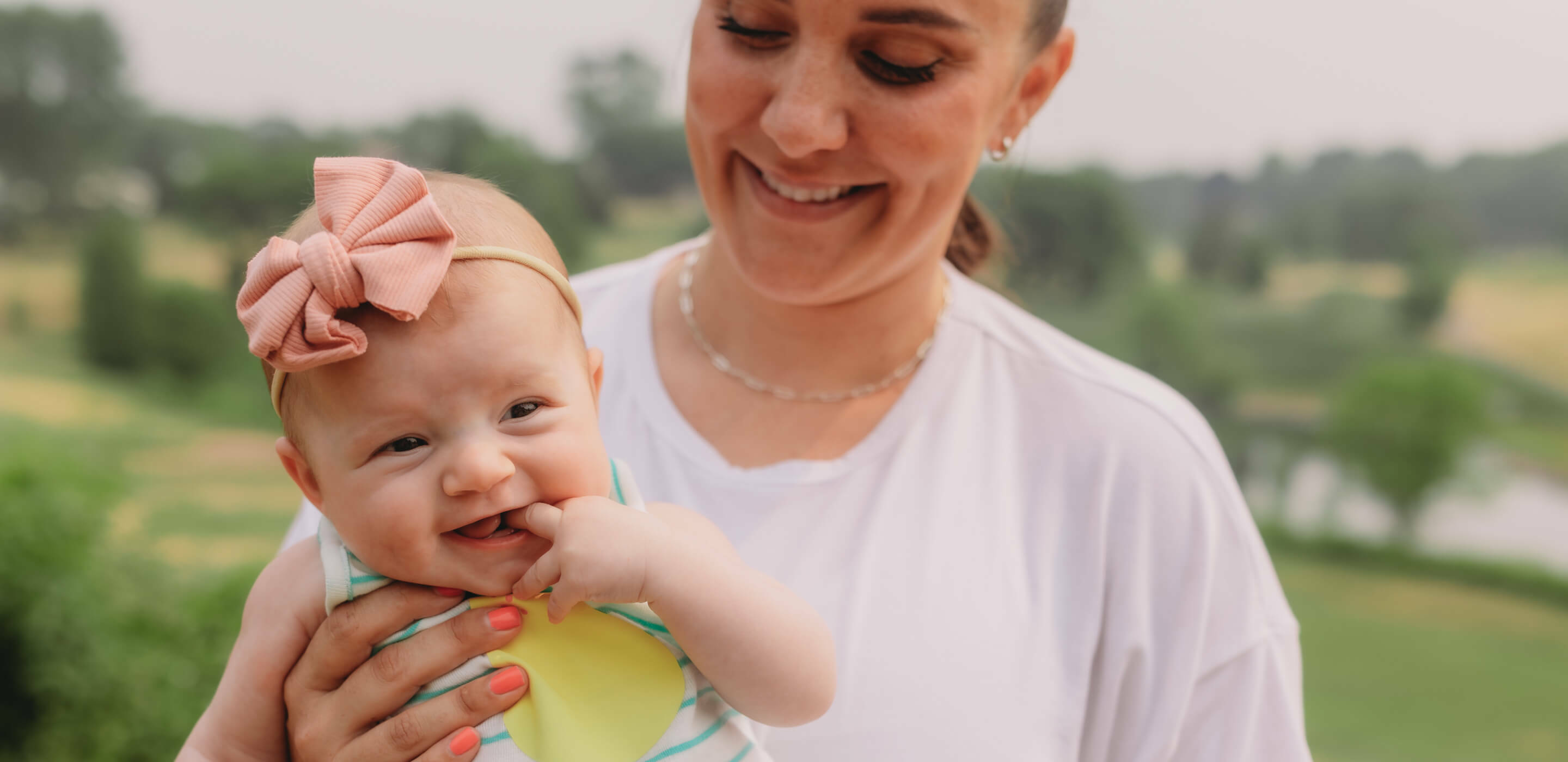 Smiling woman holding baby in field