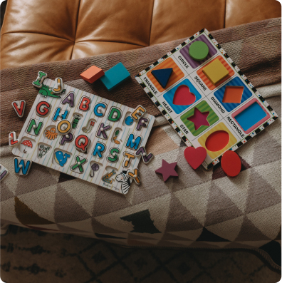 A child's toy, book, and puzzle resting on a couch