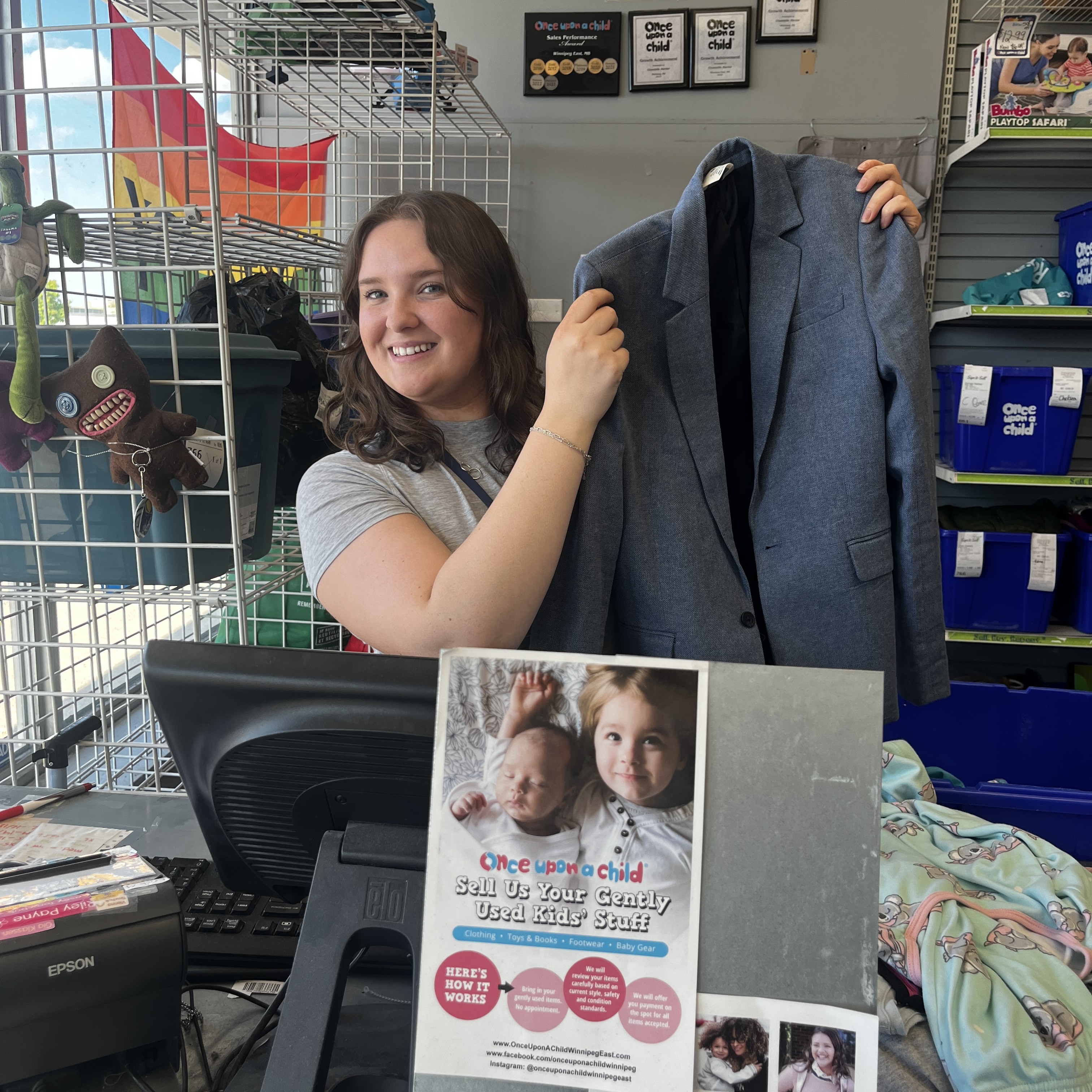 A photo of an employee holding up a blazer in front of a computer