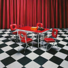 Hit Parade 1950s Formica Kitchen Table and Chairs shown with Cola Red Formica Top and Baron Red Vinyl Chairs on Checkered Floor with Red Curtain Background