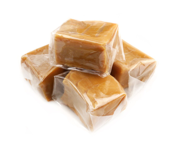 Many individually wrapped golden brown vanilla caramel squares in a 25 LB bulk case.