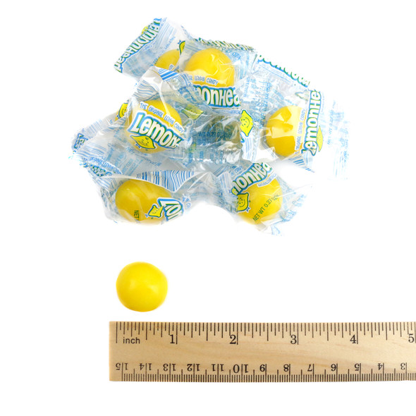 Multiple bright yellow, individually wrapped Lemonheads, round sour lemon candies with hard cores, offering a tart pucker.