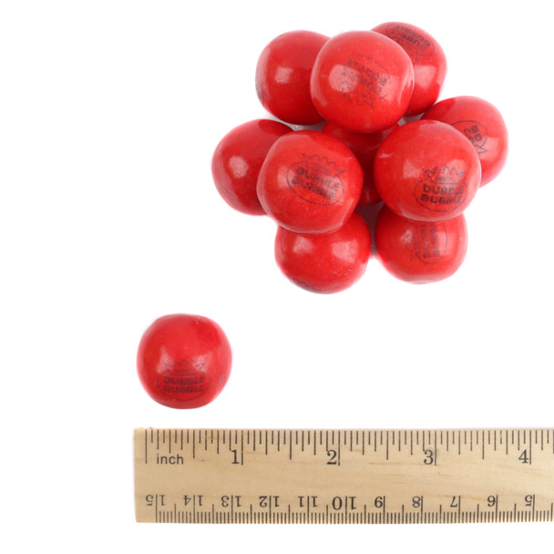 Close-up of Dubble Bubble Hot Cinnamon gumballs showing their smooth red candy shell with ruler to show size.