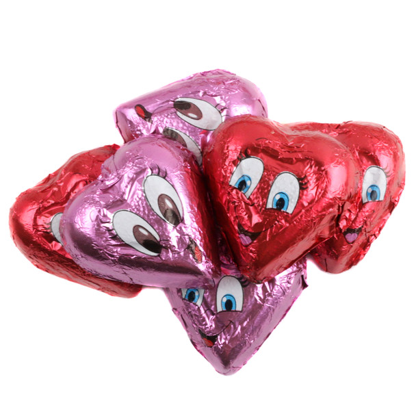 Multiple Valentine chocolate hearts with expressive faces, individually wrapped in bright red and pink foils.