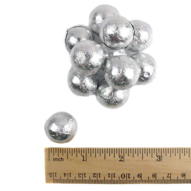 Milk chocolate ball in silver foil next to a ruler showing size