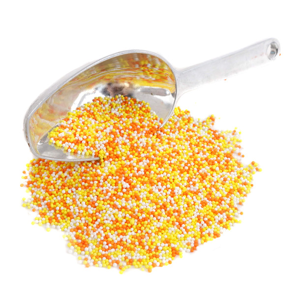 A metal spoon scooping a mix of yellow, orange, and white Candy Corn Nonpareil sprinkles