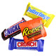 An assortment of individually wrapped fun size chocolate candy bars scattered across a clean white background.