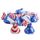 A festive pile of Hershey’s Kisses wrapped in shining red, silver, and blue patriotic foil wrappers with white plumes sticking out