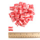 Red and white striped peppermint pillow mints with a ruler to show size.