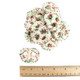 White yogurt covered pretzels, red and green nonpareils with ruler to show size.