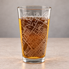 Rotated view of the State College map pint glass showing the wraparound street pattern and thick clear glass base on a stone surface.
