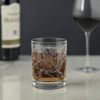 Etched map design on a double rocks whiskey glass, with intricate street detailing, set against a blurred background featuring a wine bottle and glass, highlighting a sophisticated, personalized engraved barware piece perfect for collectors and gifting.