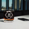 Custom laser-etched 11oz rocks glass with a heavy base and J&J Designz logo, displayed on a modern office table next to a smartphone, showcasing personalized barware for professional settings.