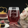 A personalized 15oz stemless wine glass featuring optional backside text in a script font. The glass is set on a marble table alongside elegant desserts and soft floral decor, ideal for anniversary celebrations.