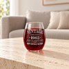 Personalized vintage stemless wine glass filled with red wine on a stone coffee table in a neutral living room.
