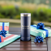 Personalized Navy Blue 22oz Stainless Steel Tumbler with name and date, with wrapped graduation gifts in the background, an ideal custom graduation present for students and alumni.