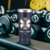 Navy blue 22oz stainless steel tumbler with a silver EMT paramedic star of life symbol laser etched on the front. The design is personalized with two lines of text. The tumbler is placed in a gym setting next to workout equipment.