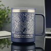 Blue stainless steel mug featuring a laser-etched map of State College, PA, showcasing precise street lines and local landmarks. Below the map, the coordinates 40°47'43.7\"N 77°51'41.8\"W and the text “STATE COLLEGE, PA” are engraved for added detail. The insulated 15oz travel mug is placed on a reflective surface, with a blurred background including a plant and a laptop, emphasizing its modern and functional design—ideal for home, office, or gifting.