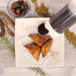 Portion Pal™ dispensing tamarind chutney with some samosas