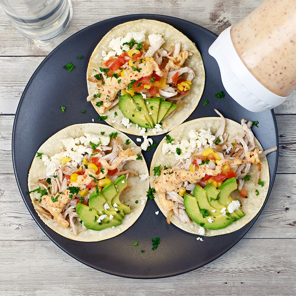 Portion Pal™ dispensing tajin crema onto three tacos