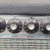 Detail of the Fender Bassman 100 control knobs showing a chipped Middle knob, scratches on the silverface panel, and fraying along the upper edge of the grille cloth. card