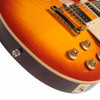 Angled close-up of the Les Paul lower body showing the flame maple figuring, cream binding, chrome bridge and tailpiece, control knobs, and output jack. card