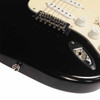 Close-up of black Squier Strat body near the tremolo bridge and output jack showing light surface marks and scratches. card