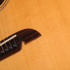 Close view of guitar top and bridge showing a visible linear finish mark extending above the bridge. card