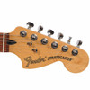 Close-up of the maple Fender Stratocaster headstock showing the logo, six chrome tuning machines, string trees, and nut. card