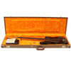 Fender Precision Bass resting inside an open brown hardshell case with orange plush interior and included paperwork. card