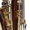 Close-up of saxophone body and keywork showing scratches and lacquer wear near the key posts. card