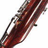 Close-up of significant finish wear exposing lighter wood, scratches, and scuffs near the bassoon's keys. card