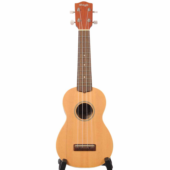 Full front view of the Stagg US60-S soprano ukulele with natural finish on a display stand.