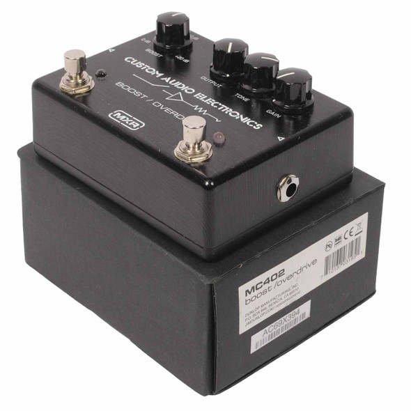 Three-quarter view of the MXR MC402 Custom Audio Electronics Boost/Overdrive pedal displayed on its original product box. card