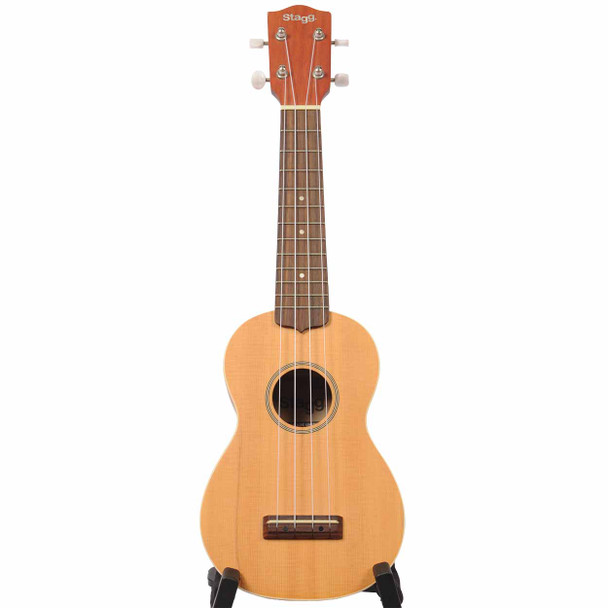 Full front view of the Stagg US60-S soprano ukulele with natural finish on a display stand.