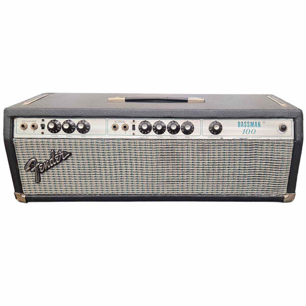 Front view of a 1977 Fender Bassman 100 amplifier head with black covering, silverface control panel, blue-and-silver grille cloth, and Fender logo. card