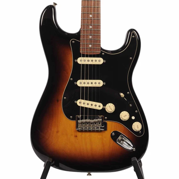 Close-up front view of the Fender Deluxe Stratocaster body showing the 2-Color Sunburst finish, black pickguard, three cream single-coil pickups, and chrome bridge. card