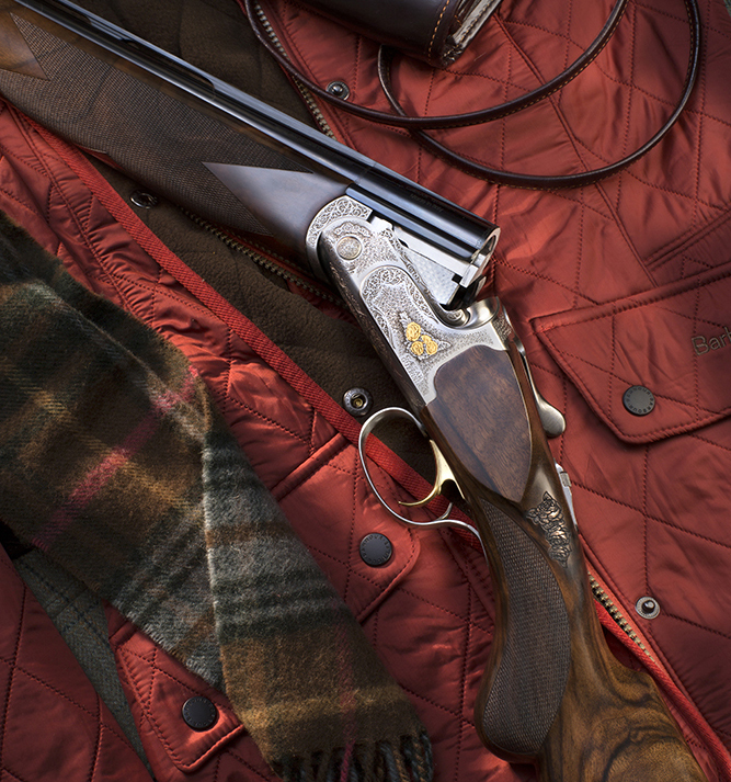 Over/under shotgun resting on quilted jacket and tartan scarf