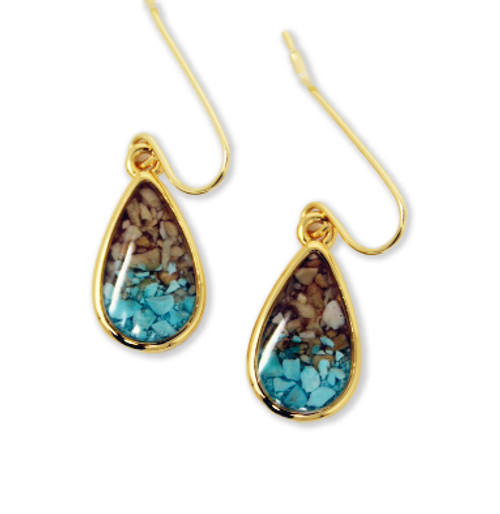 Image shows a close-up of gold teardrop earrings featuring natural elements sourced from the Dead Sea.