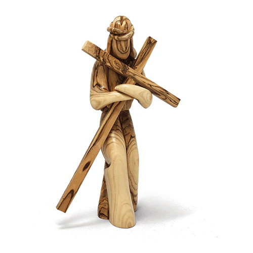 The image shows Jesus with a standing cross figurine made from olive wood. 