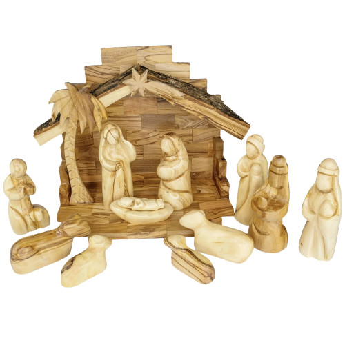 The image shows the Nativity set made of olive wood and set in a bark-roof stable 