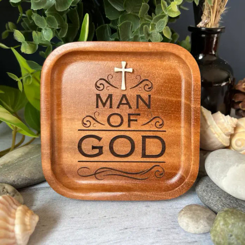 The image shows the "Man of God" trinket dish surrounded by seashells and greenery.