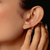 The image shows a woman wearing these mother-of-pearl cross-dome stud earrings.