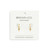 The image shows a gold set of cross huggie earrings on its packaging. 