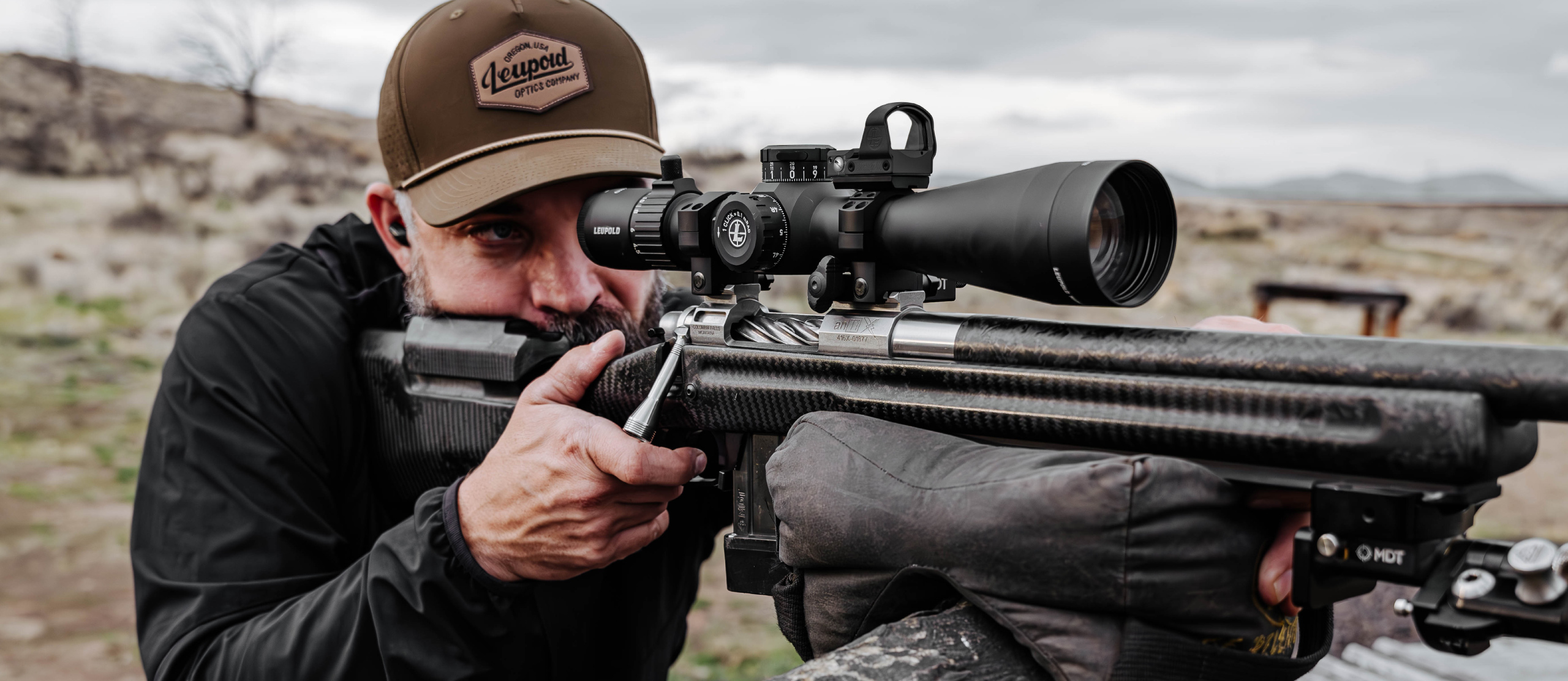 A man shooting a rifle with a Leupold Mark 4HD scope.