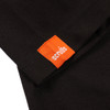 Close-up of bright orange Scruffs brand fabric tab woven into the cuff hem of a black long sleeve t-shirt