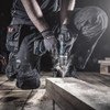 Scruffs Trade Flex Trousers worn by tradesperson kneeling while drilling on site