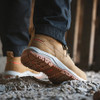 Scruffs Ridge tan safety boots worn on rough ground, showing the orange tread outsole and work boot profile