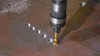 HMT VersaDrive Spiral Flute ImpactaTap - Imperial – close-up of a spiral-flute tap cutting steel with a drill