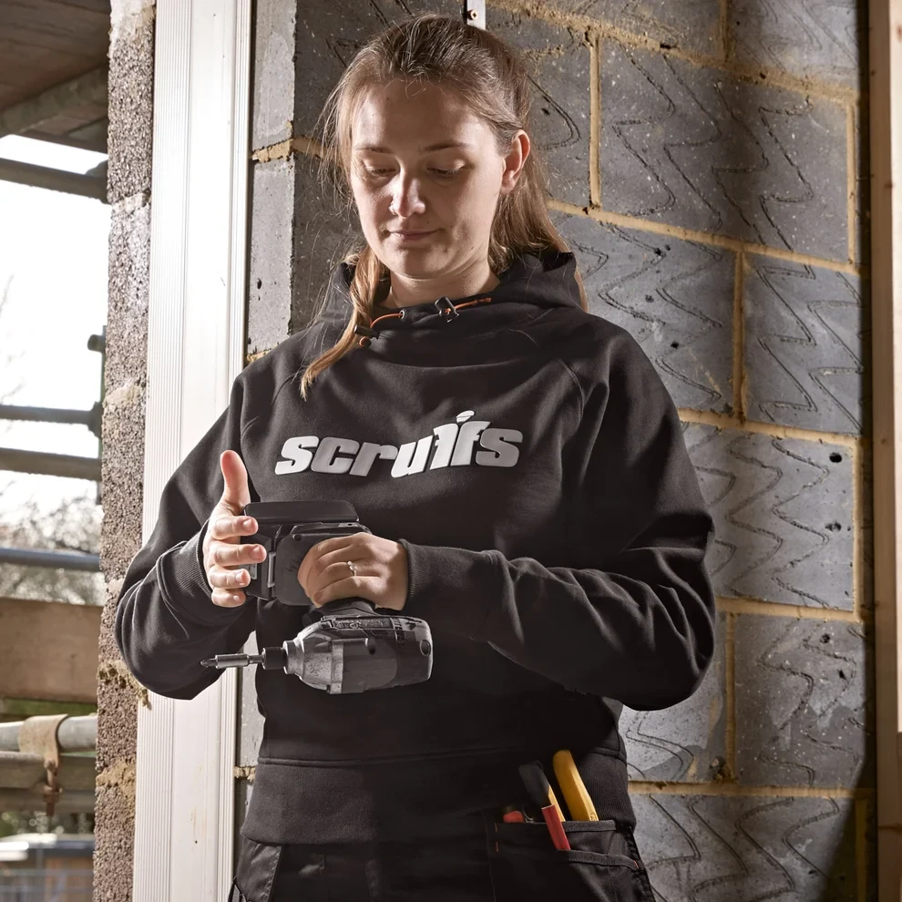 Scruffs Women's Tamworth Logo Hoodie worn by female tradesperson using power tool